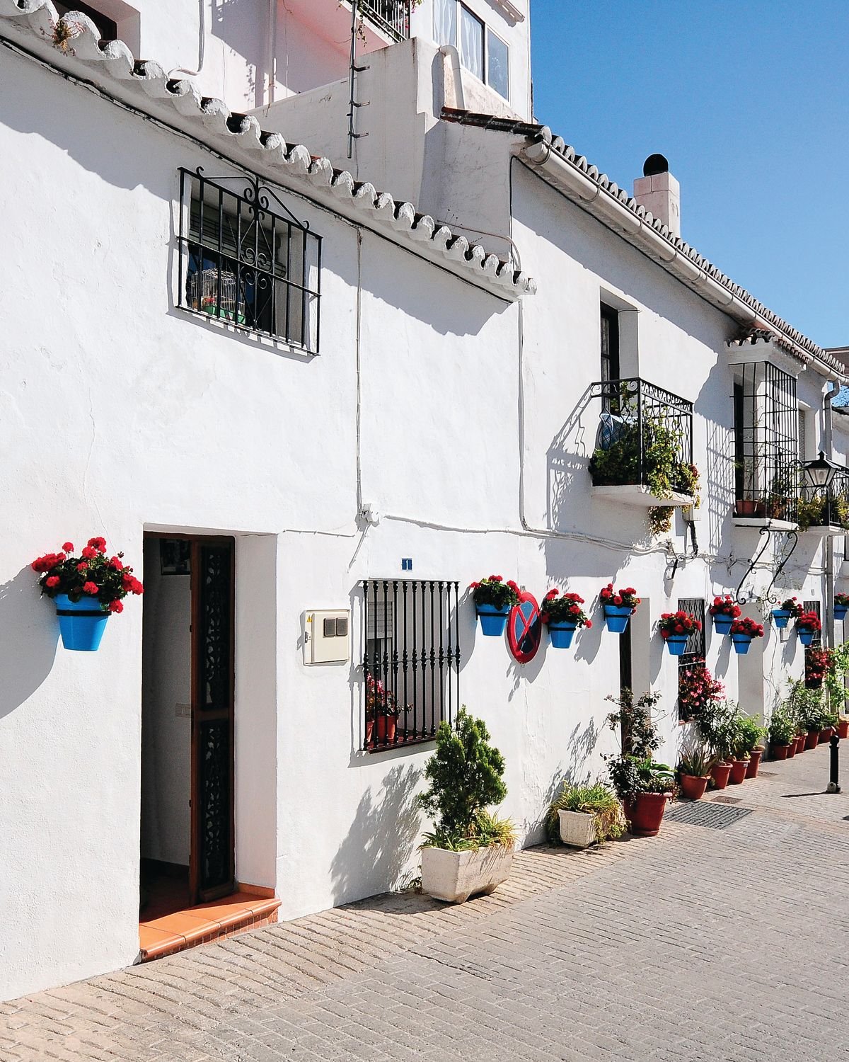 Calle Muro in Mijas Pueblo, a whitewashed street with blue flowerpots.